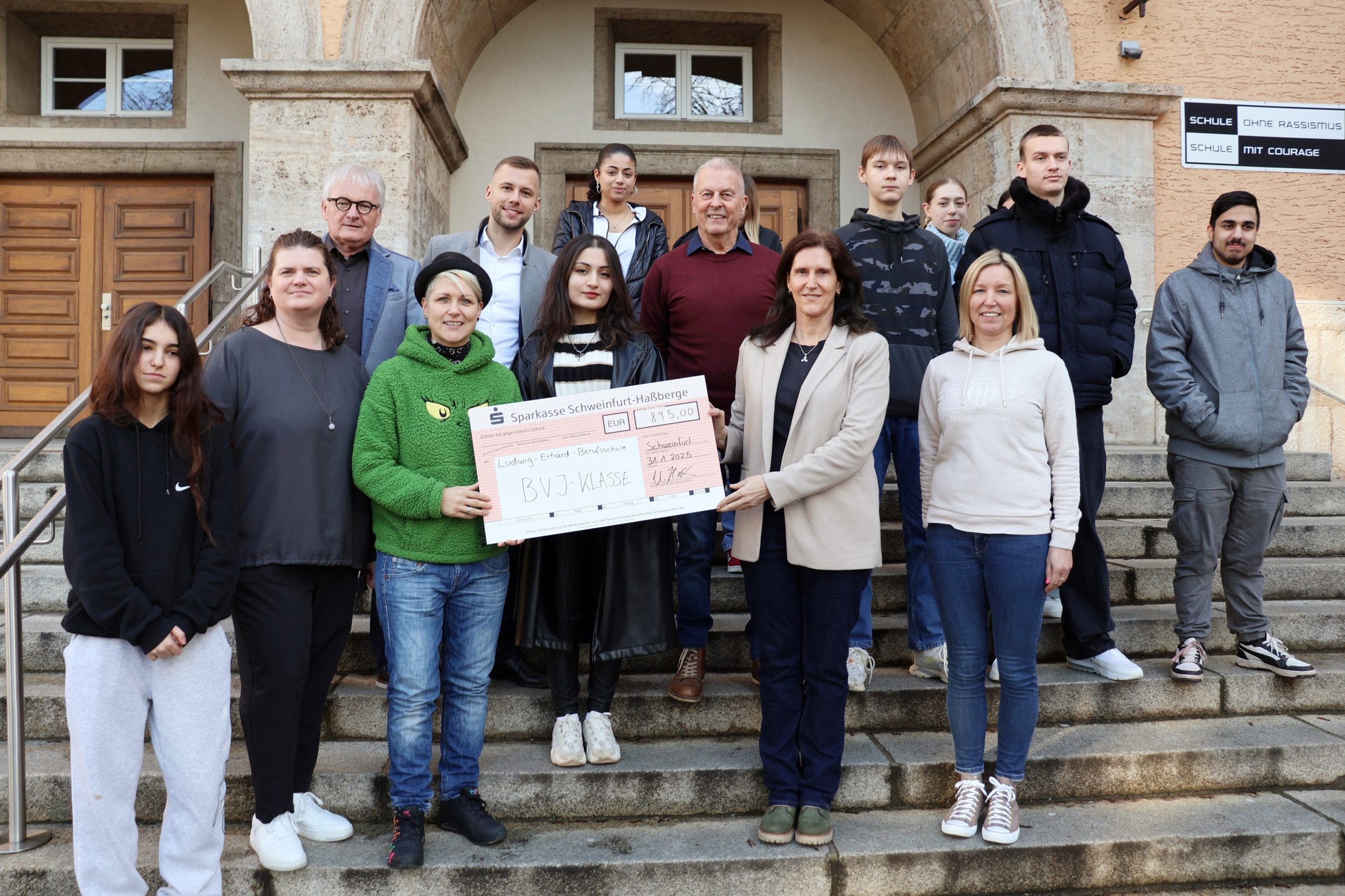 Auf dem Bild halten Kindertafel-Botschafterin Steffi List (grünes Oberteil) und Schulleiterin Ulrike Hoch den Scheck, dazwischen Klassensprecherin Zerin Belal, rechts Klassenlehrerin Anja Schölch. Links neben List und darüber gegen den Uhrzeigersinn Projektleiterin und Lehrerin Tina Sauer und zwischen den Kindertafel-Vorständen Stefan Labus und Rainer Zink steht Alexander Kuckshaus, Center-Manager der Stadtgalerie Schweinfurt. Foto: Michael Horling